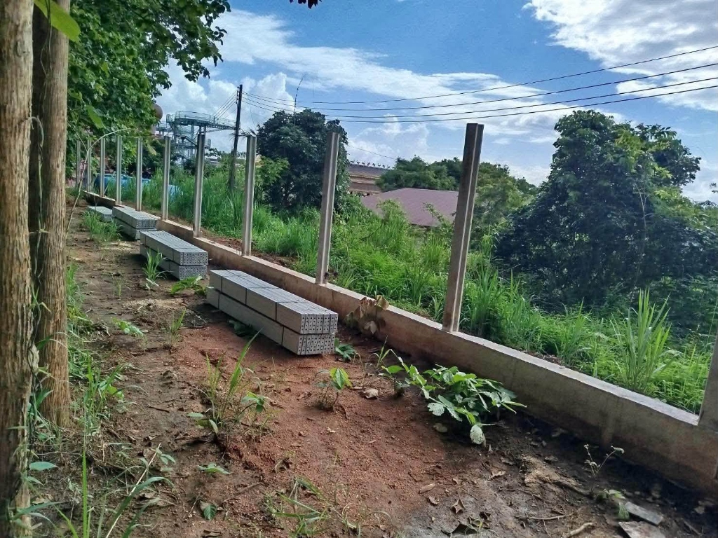 แผ่นปูนซีเมนต์จัดวางเรียงตามแนวเสารั้วคอนกรีตรอบอาณาเขตวัด